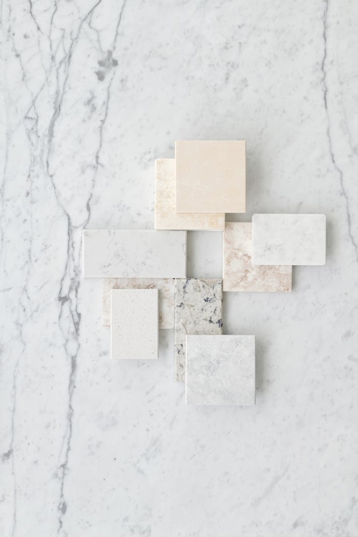 ours-journey Aesthetic flat lay of various marble tiles arranged on a textured marble surface.