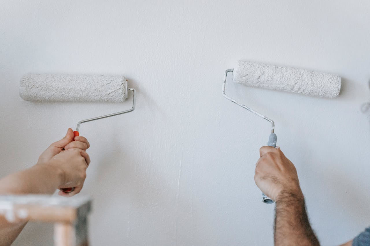 The Art of Drawing Readers In: Your attractive post title goes here Close-up of two individuals painting a wall with paint rollers indoors.